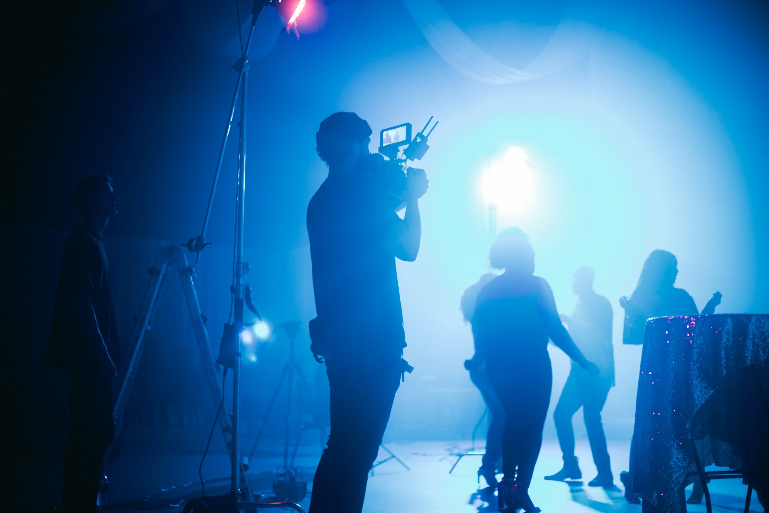 A person holding a camera on set silhouetted against a bright light while they are filming a scene